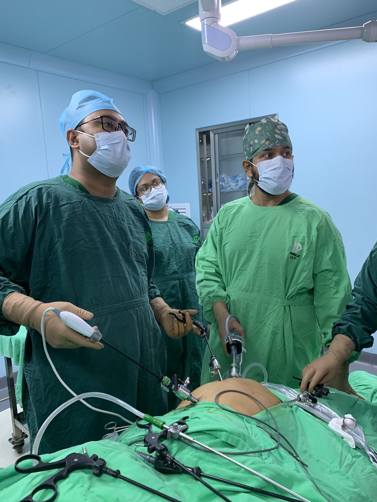 Masked surgical team using laparoscopic instruments for biliary surgery Bangladesh in a sterile operating theatre.